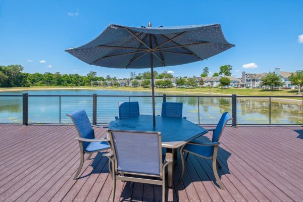 Patio beside the sundeck with table seating under umbrellas with the lake on the other side