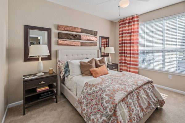 Carpeted bedroom with a full bed, nightstands on either side, and a large window