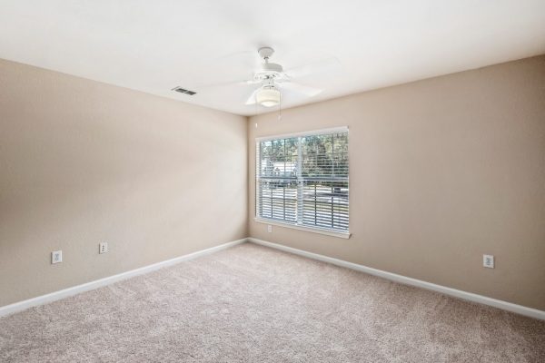 Unfurnished, carpeted bedroom with ceiling fan
