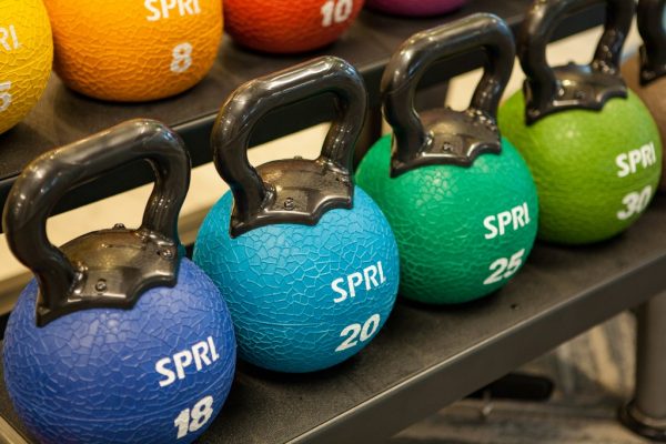 Four colorful kettlebell weights ranging from 18 to 30 pounds