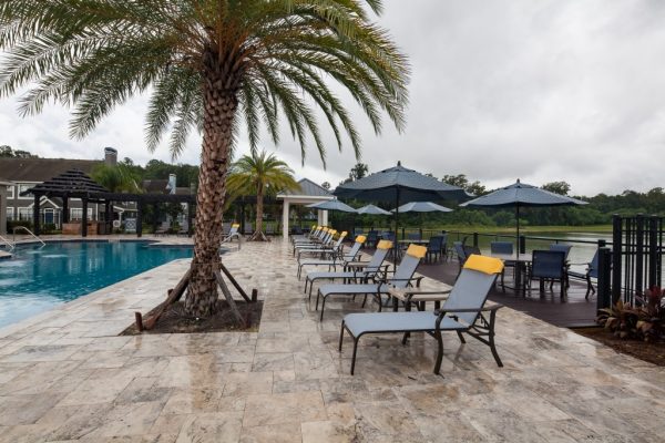 Poolside sundeck with lounge chairs and table seating with a view of the lake in the background