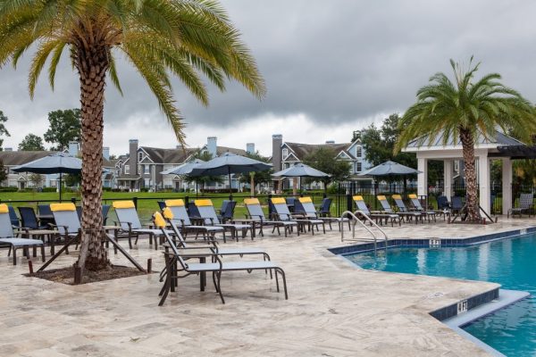 Poolside sundeck with lounge chairs and table seating with a view of the lake in the background