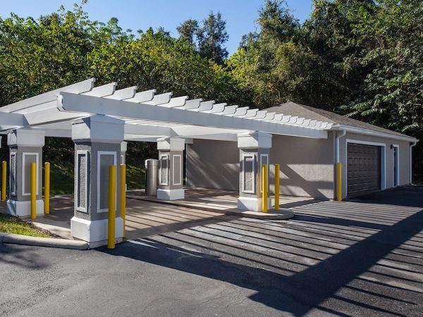 Car care center with four parking spots under a pergola with trash cans, vacuums, and a garage space to the right